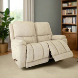 Reclining loveseat in light beige fabric with plush cushions and extended footrest