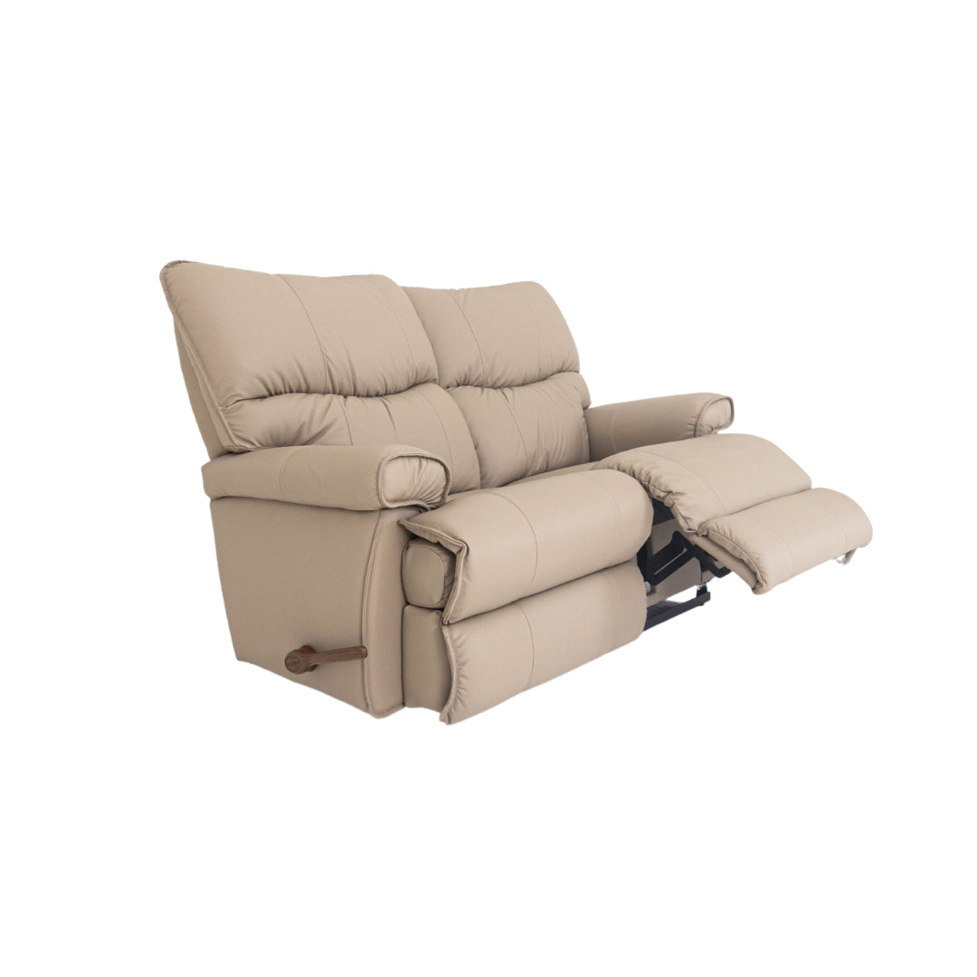 Light beige leather motion reclining loveseat with padded arms and extended footrest