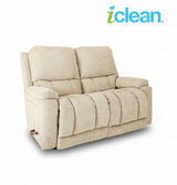 Reclining loveseat with light beige upholstery and padded armrests, reclining seats