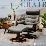 Dark leather pedestal lounge chair with wide ottoman and round wooden base