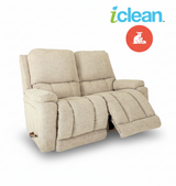 Fabric reclining loveseat with extended footrest and padded arms in light beige